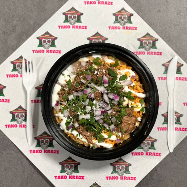 Tako Kraze Mexican rice bowl with shredded meat, beans, sour cream, cilantro, and red onions.